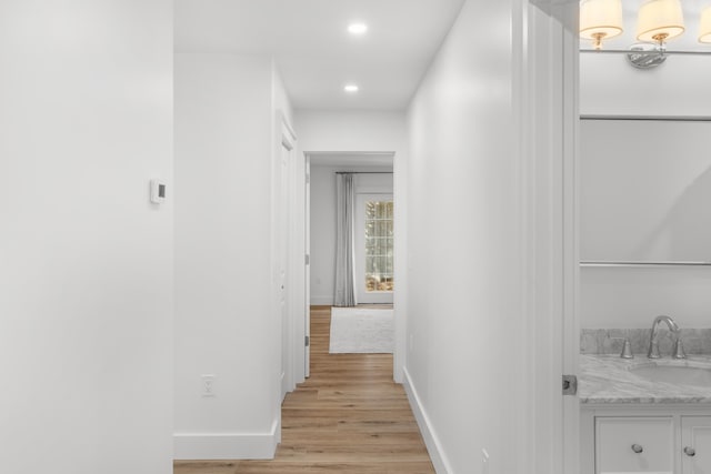 corridor with light hardwood / wood-style flooring and sink