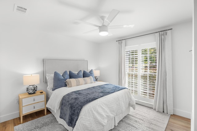 bedroom with visible vents, baseboards, wood finished floors, and ceiling fan