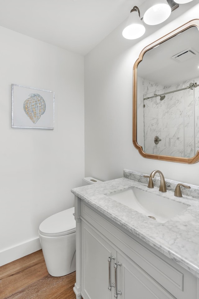 full bath with wood finished floors, vanity, walk in shower, toilet, and visible vents