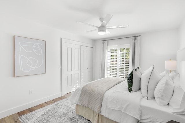 bedroom with ceiling fan, baseboards, wood finished floors, and a closet