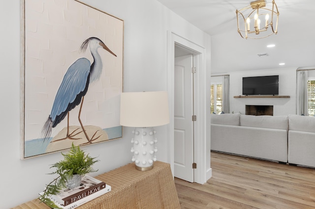 hall featuring light wood-type flooring, a wealth of natural light, a notable chandelier, and recessed lighting