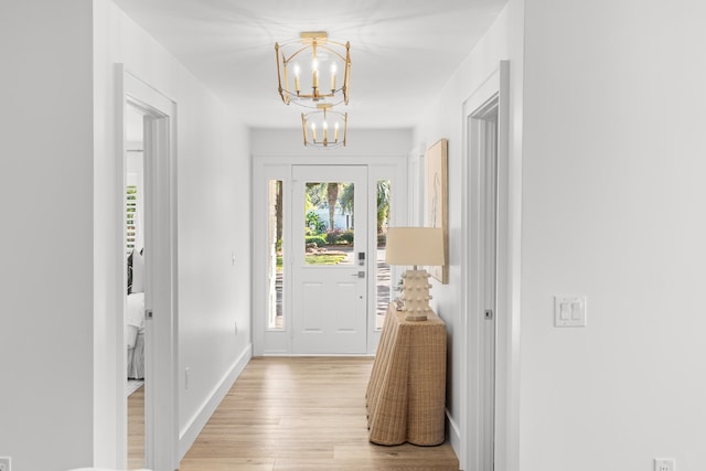 doorway to outside with an inviting chandelier and light wood-type flooring