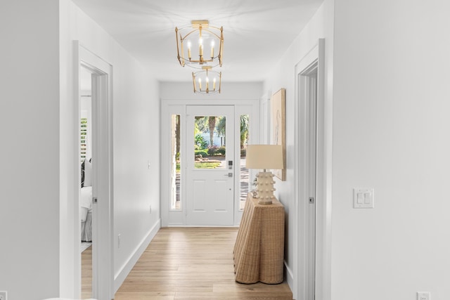 foyer entrance with baseboards, a notable chandelier, and light wood-style flooring