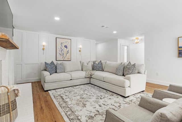 living area with a decorative wall, visible vents, light wood finished floors, and recessed lighting