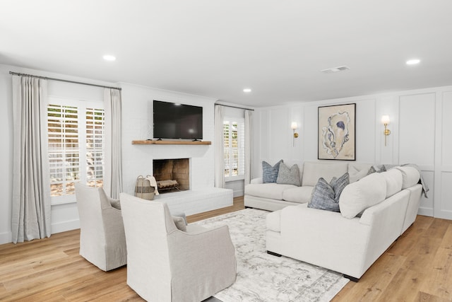 living room featuring a wealth of natural light, light hardwood / wood-style flooring, and a fireplace