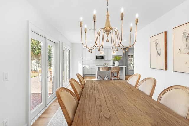 dining area featuring a chandelier, visible vents, and light wood finished floors