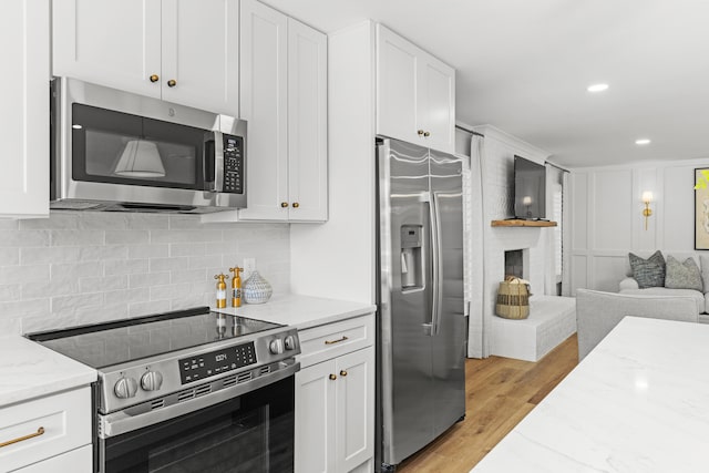 kitchen with light hardwood / wood-style flooring, white cabinetry, light stone countertops, and stainless steel appliances