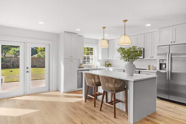 kitchen with light countertops, a center island, tasteful backsplash, appliances with stainless steel finishes, and a breakfast bar area