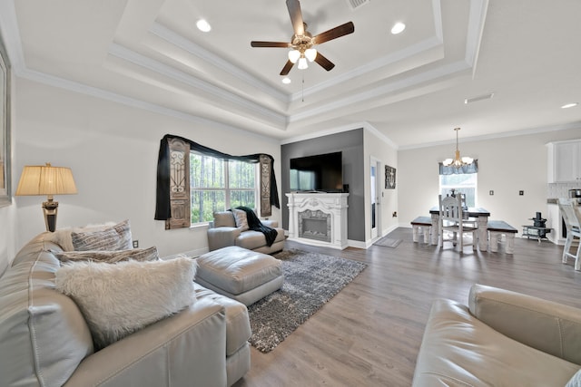 living room with ornamental molding, a tray ceiling, and wood finished floors