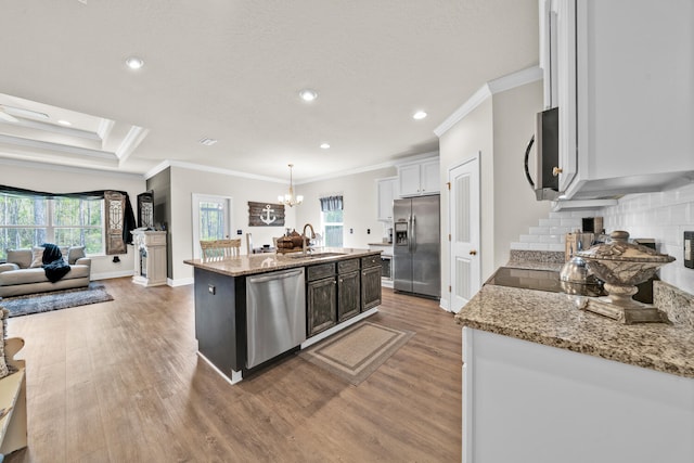 kitchen with hanging light fixtures, sink, a kitchen island with sink, white cabinetry, and appliances with stainless steel finishes