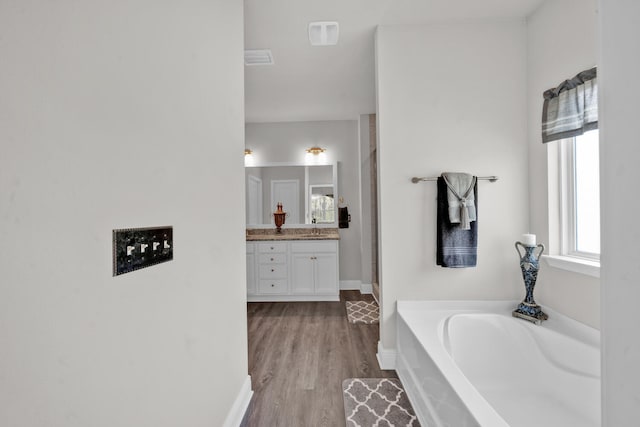 bathroom with wood-type flooring, vanity, and a tub