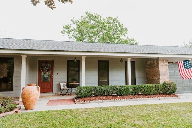 entrance to property with a lawn, a garage, and covered porch