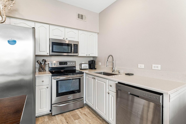 kitchen with light hardwood / wood-style flooring, stainless steel appliances, sink, and white cabinetry