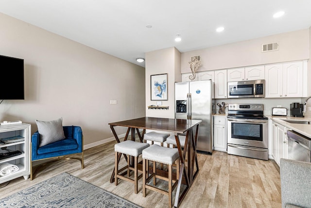 kitchen with visible vents, appliances with stainless steel finishes, light countertops, light wood-style floors, and white cabinetry
