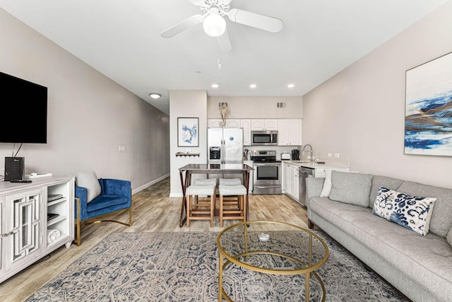 living room featuring light hardwood / wood-style floors, sink, and ceiling fan