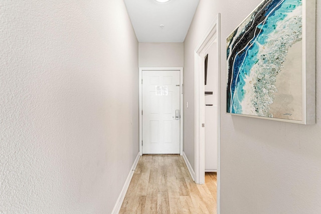 hallway featuring baseboards and light wood finished floors