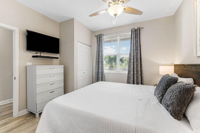 bedroom featuring baseboards, a ceiling fan, light wood finished floors, and a closet