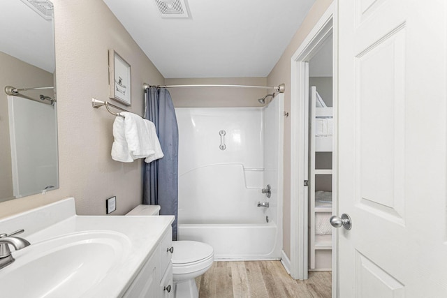 bathroom featuring visible vents, wood finished floors, vanity, toilet, and shower / bathtub combination with curtain