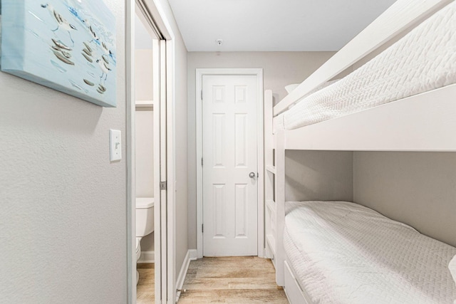 bedroom featuring light hardwood / wood-style flooring and ensuite bath