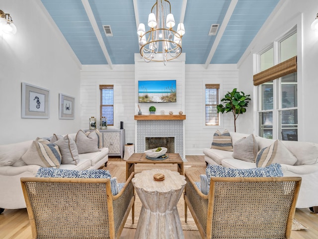 147 Silver Laurel Way, Santa Rosa Beach, FL 32459 - living area featuring lofted ceiling with beams, light wood-style floors, a chandelier, a tile fireplace, and visible vents
