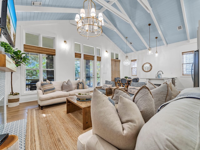 living room with a notable chandelier, beam ceiling, hardwood / wood-style flooring, and high vaulted ceiling