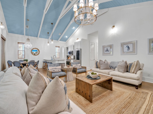 living room with a notable chandelier, beam ceiling, high vaulted ceiling, and light wood-type flooring