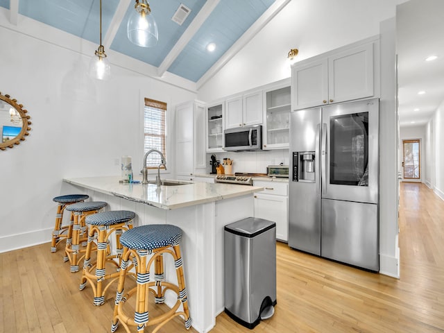 kitchen featuring white cabinetry, lofted ceiling with beams, appliances with stainless steel finishes, and decorative light fixtures