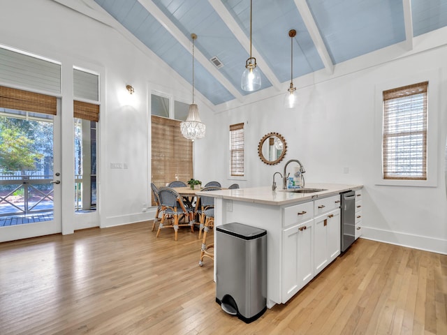 kitchen featuring sink, lofted ceiling with beams, pendant lighting, white cabinets, and light hardwood / wood-style floors