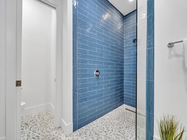 bathroom featuring tile patterned floors, a tile shower, and toilet