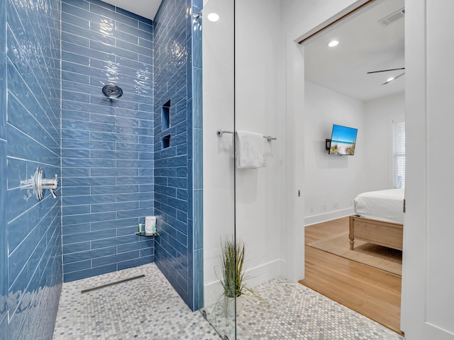 bathroom with tiled shower and hardwood / wood-style floors