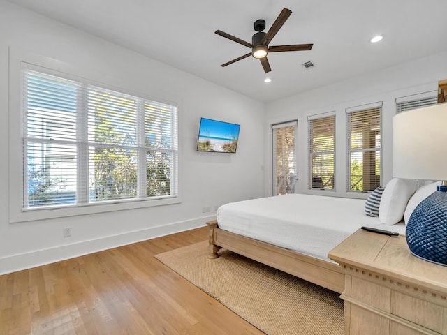 bedroom featuring multiple windows, hardwood / wood-style floors, and ceiling fan