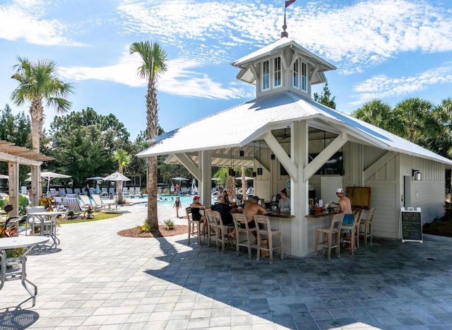 view of property's community featuring a patio area, a bar, and a swimming pool