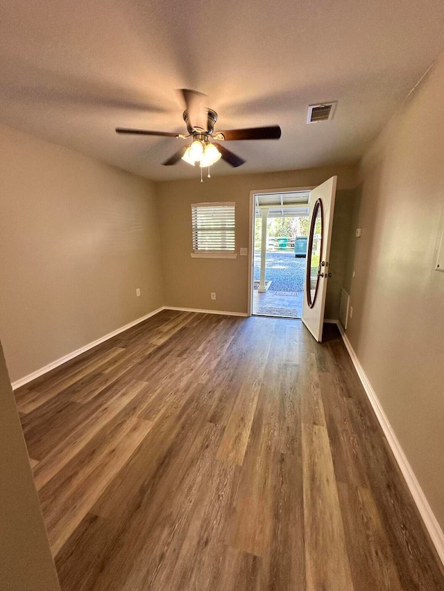 spare room with a textured ceiling, ceiling fan, and dark wood-type flooring