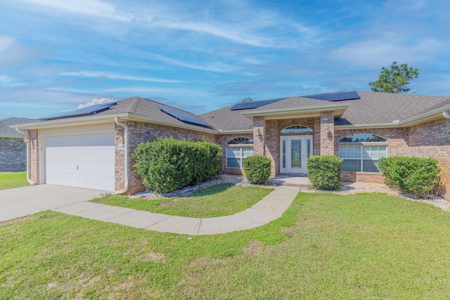 ranch-style house featuring a garage, solar panels, and a front lawn