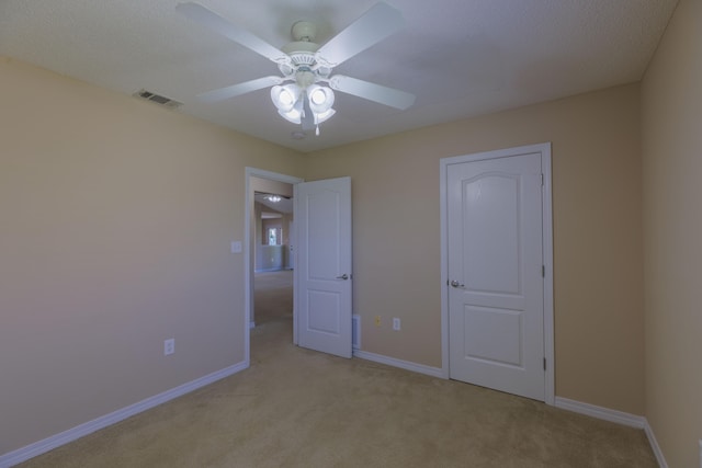 unfurnished bedroom featuring ceiling fan, a textured ceiling, and light carpet