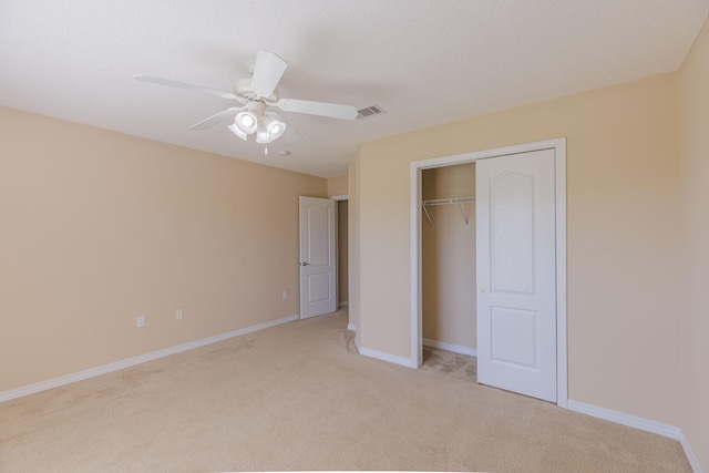 unfurnished bedroom with ceiling fan, a textured ceiling, a closet, and light carpet