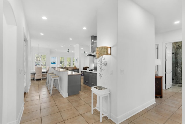 kitchen with a kitchen breakfast bar, light tile patterned flooring, a center island, and extractor fan