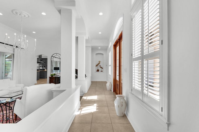 hall with a notable chandelier and light tile patterned flooring