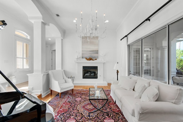 living room with a notable chandelier, a wealth of natural light, hardwood / wood-style flooring, and ornamental molding