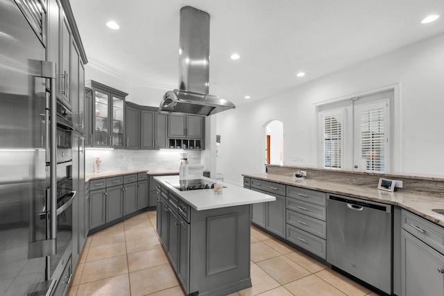 kitchen with a center island, light tile patterned flooring, island range hood, gray cabinetry, and black appliances