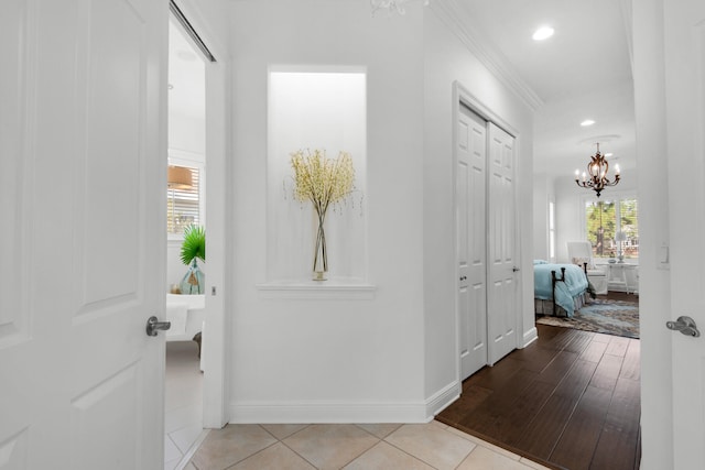 hallway featuring crown molding, light hardwood / wood-style floors, and a chandelier