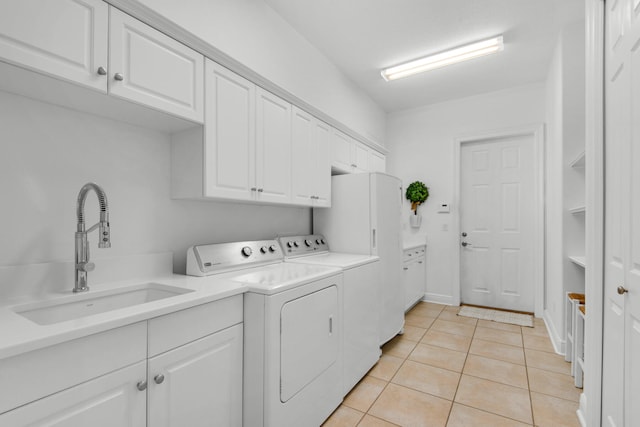 laundry area with cabinets, light tile patterned floors, separate washer and dryer, and sink