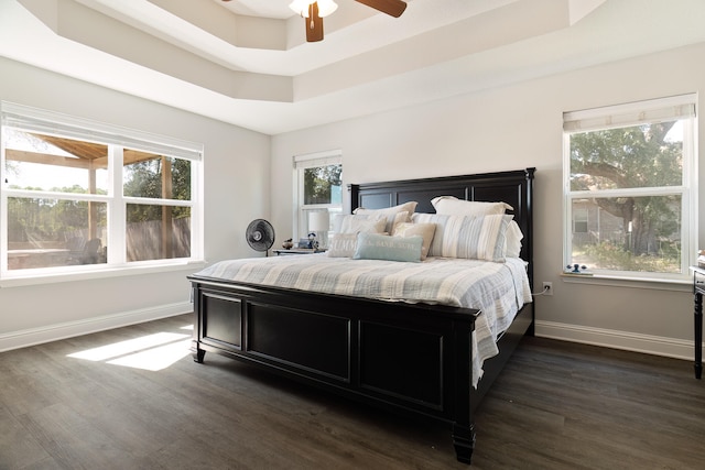 bedroom featuring dark wood-type flooring, ceiling fan, and a raised ceiling