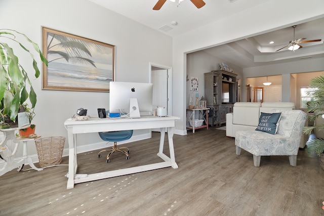 office area featuring ceiling fan, a raised ceiling, and wood-type flooring