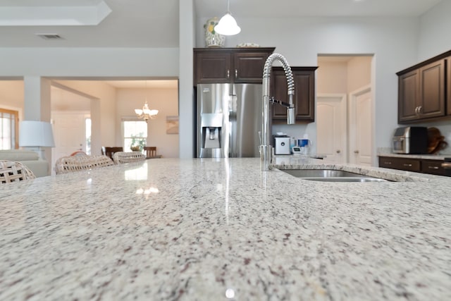 kitchen with light stone counters, a healthy amount of sunlight, and stainless steel fridge