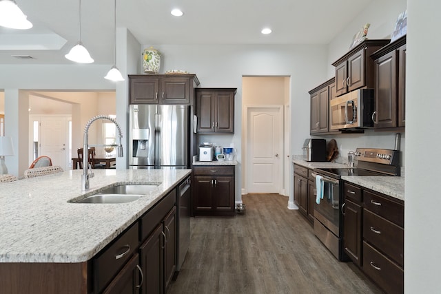 kitchen with sink, an island with sink, dark hardwood / wood-style flooring, stainless steel appliances, and pendant lighting