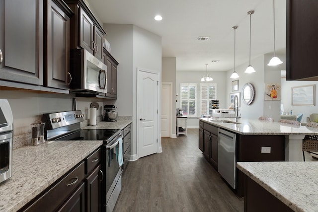 kitchen with dark hardwood / wood-style floors, stainless steel appliances, sink, decorative light fixtures, and an inviting chandelier