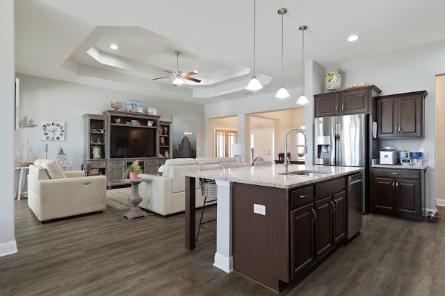 kitchen with a kitchen island with sink, dark hardwood / wood-style floors, a kitchen breakfast bar, hanging light fixtures, and sink