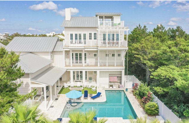 rear view of property featuring a balcony, a fenced in pool, and a patio area