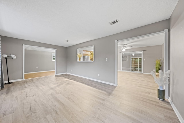 empty room with a textured ceiling, ceiling fan, and light hardwood / wood-style flooring